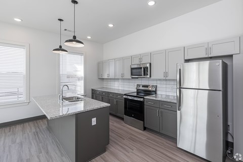 A modern kitchen with a refrigerator, sink, and stove.
